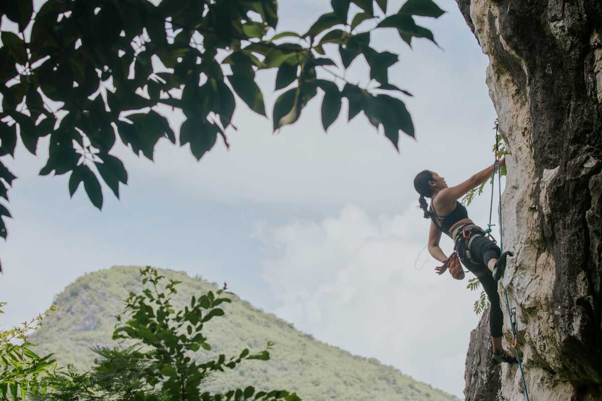 Rock climber scaling a limestone cliff at Railay Beach, Krabi, Thailand