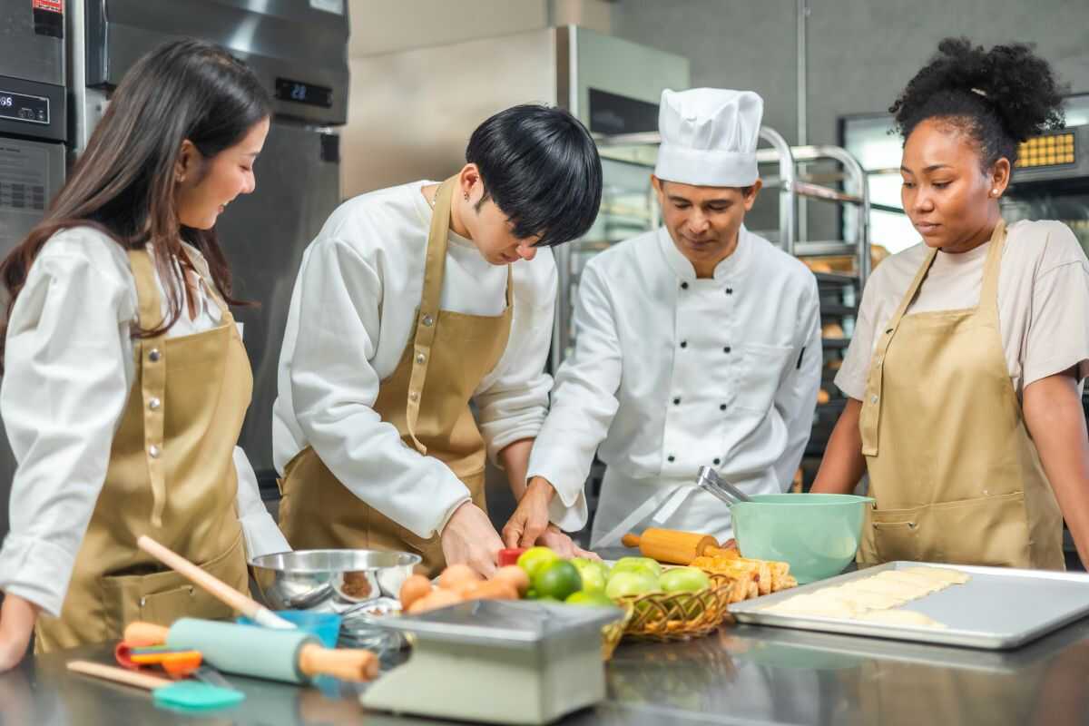 A group of travelers wearing aprons, cooking Thai dishes under the guidance of a local chef.