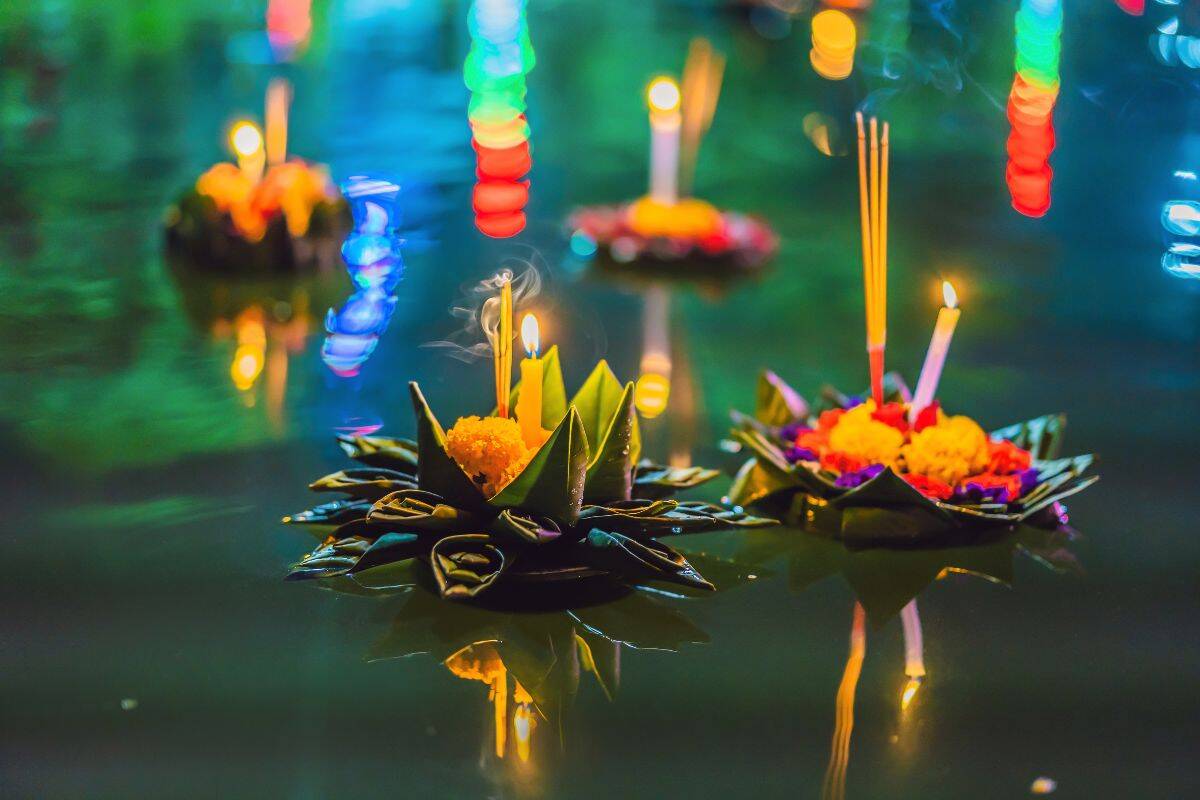 Candle-lit krathongs floating on a river during Loy Krathong Festival in Thailand 2025